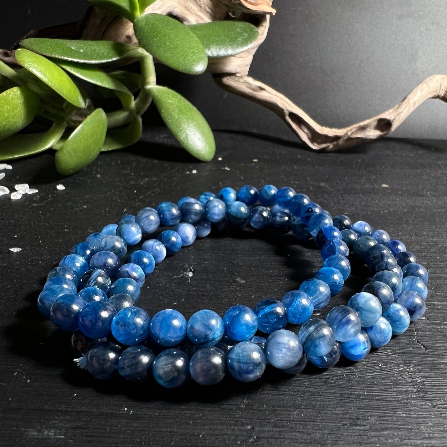 Drei blaue Kyanit Armbänder gestapelt auf schwarzem Holz