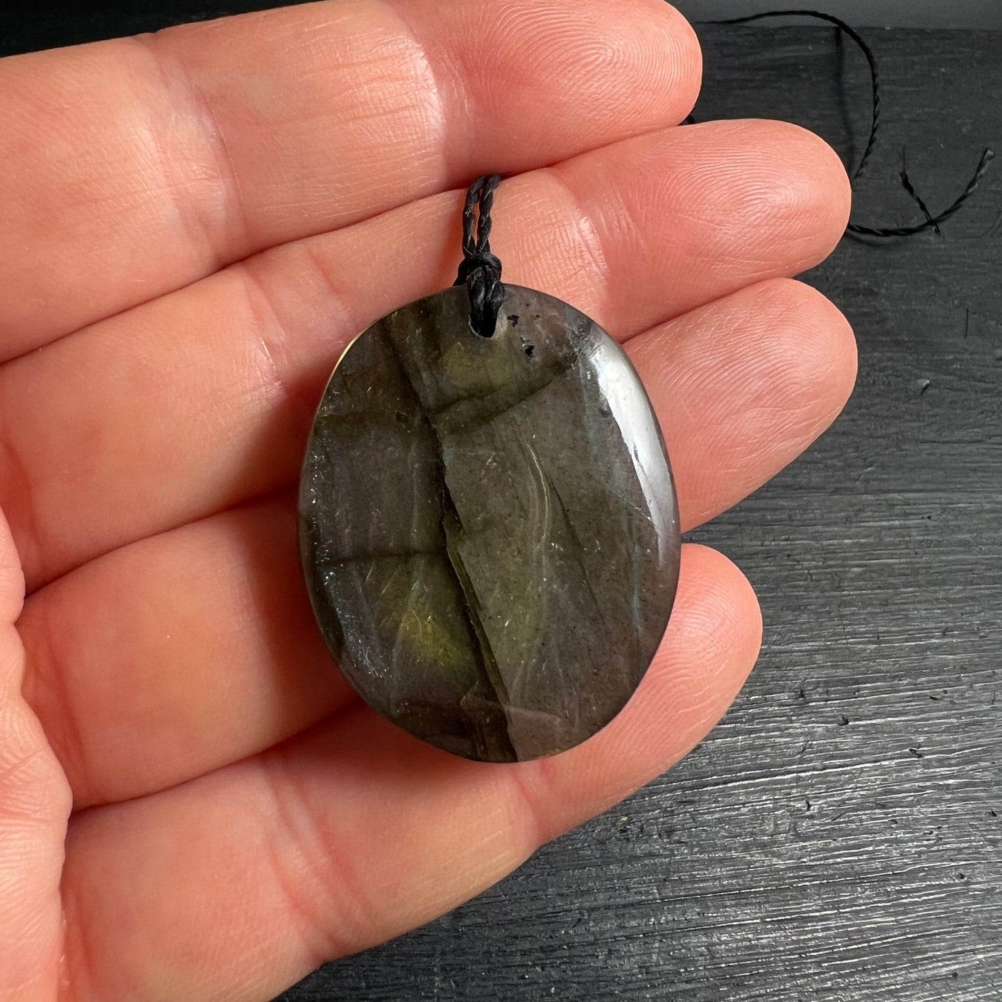 Labradorit Anhänger oval poliert, dunkelgrün-schwarz mit gelbgrünem Labradoreszenz-Schimmer, Cleavage-Muster sichtbar | Happy Minerals