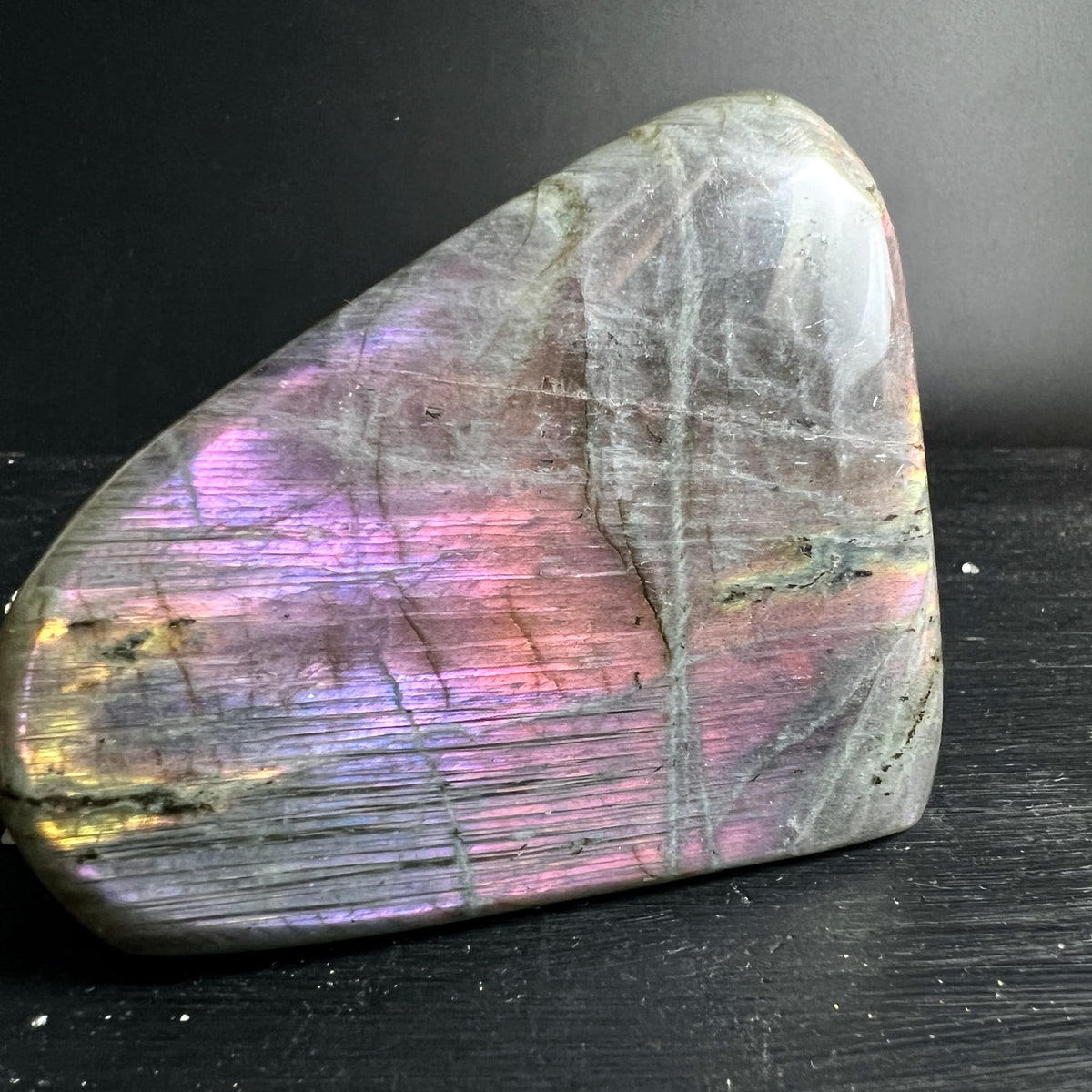 Labradorit Freiform mit violett-pinkem und goldenem Schiller auf grauem Untergrund, polierte Oberflaeche | Happy Minerals