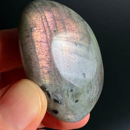 Labradorit Handschmeichler oval-poliert, grau-grüner Grundton mit rosafarbenem Labradoreszenz-Schimmer, dunkle Einschlüsse | Happy Minerals