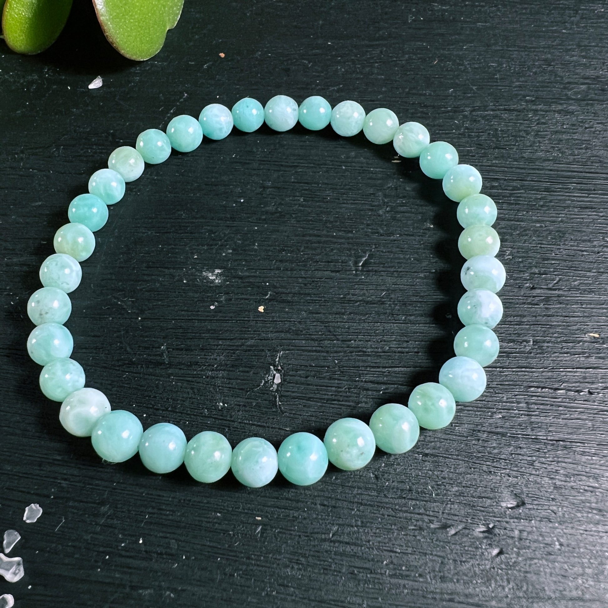 Larimar Perlenarmband | Kreisform liegend | meeresblau schimmernd | Holzuntergrund | Happy Minerals
