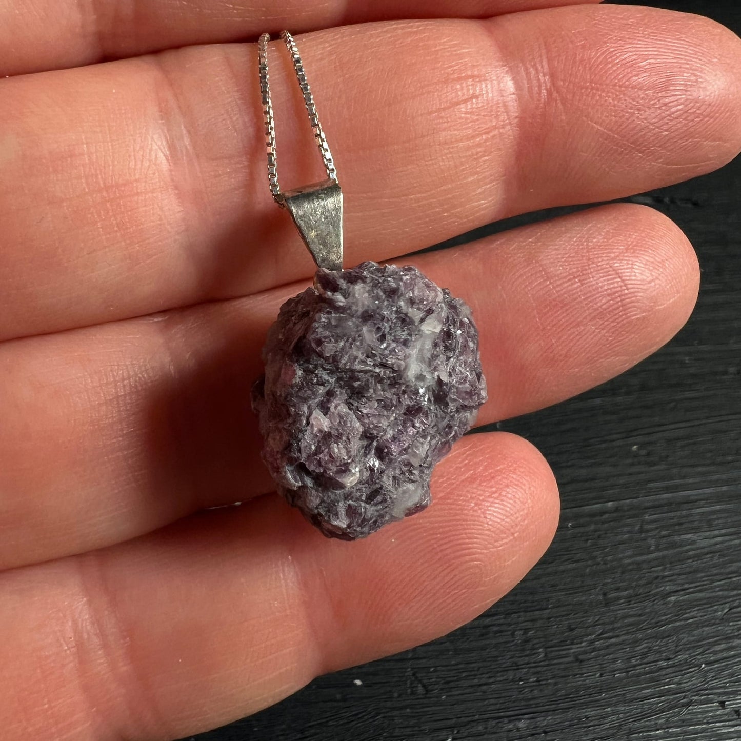 Lepidolith Anhaenger roh, violett-grau glitzernde Glimmerschuppen, an Silberkette zwischen Fingern gehalten | Happy Minerals