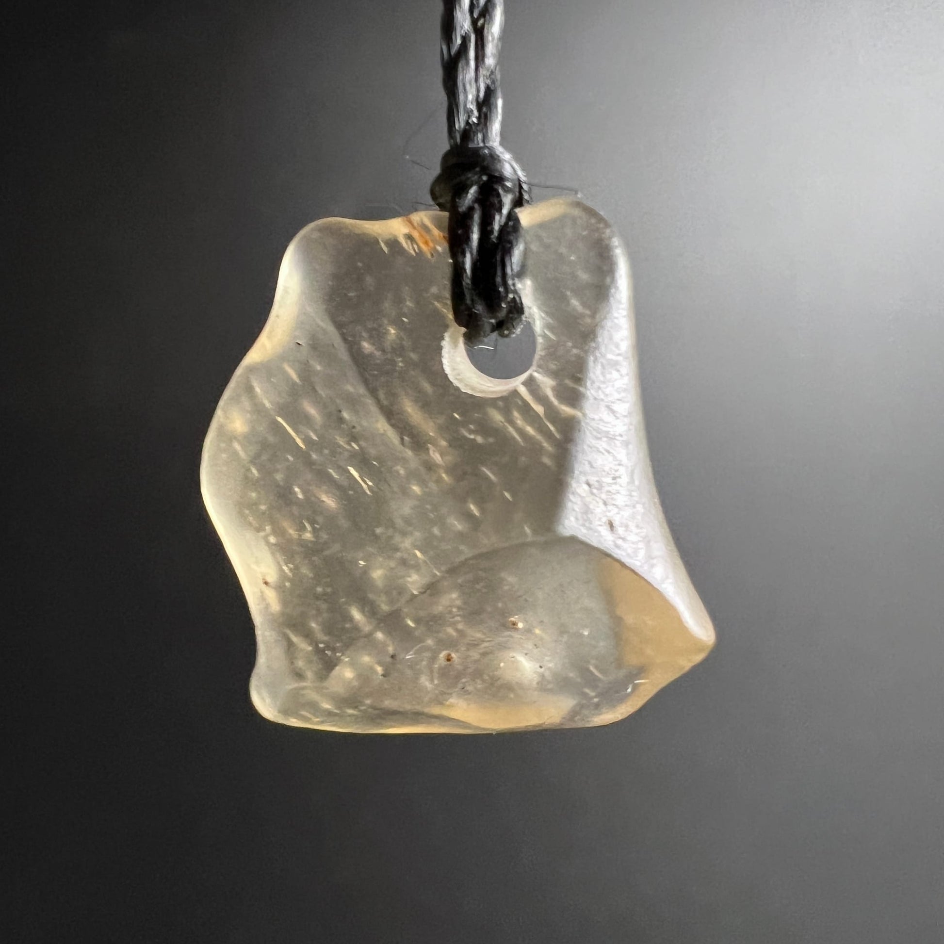 Libysches Glas hängend | freigestellt vor grauem Hintergrund | warmes Gelbgold | Happy Minerals