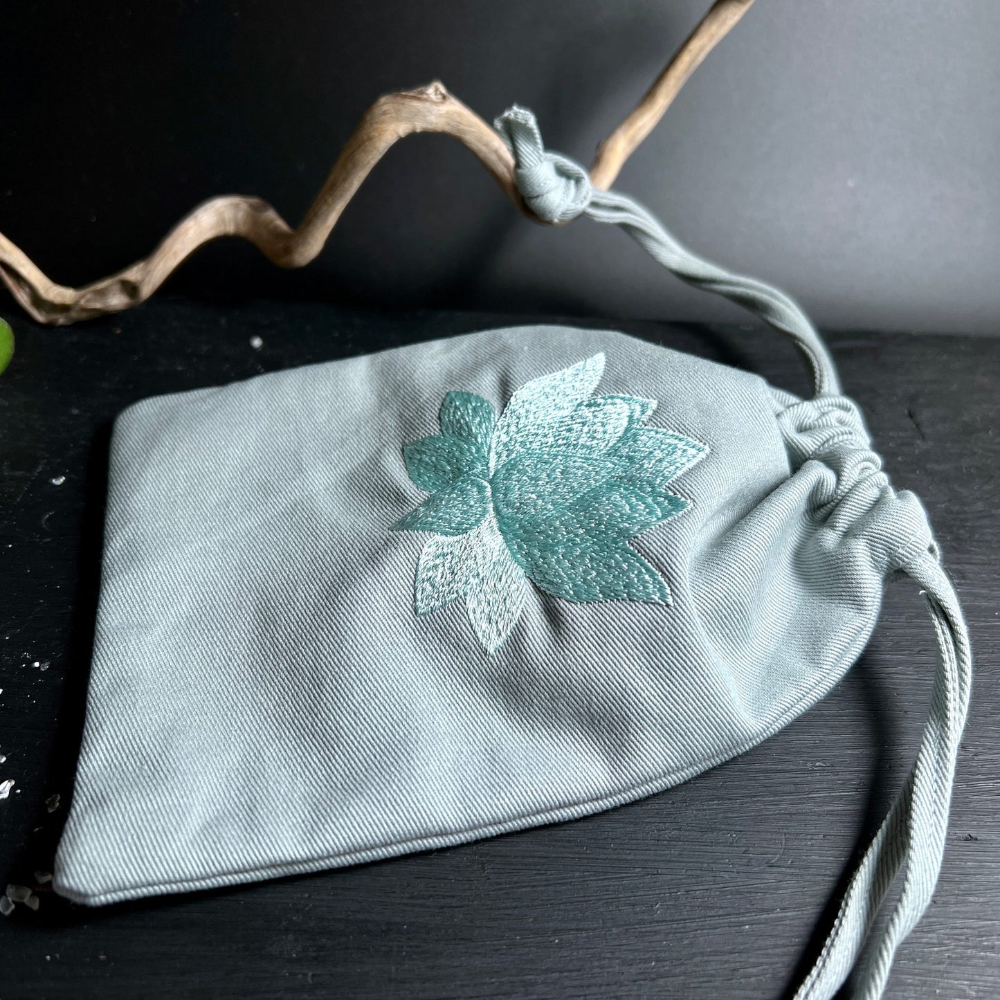 Detailansicht Stoffbeutel | türkise Lotusblüte Stickerei | grauer Stoff | geschlossener Kordelzug | Happy Minerals