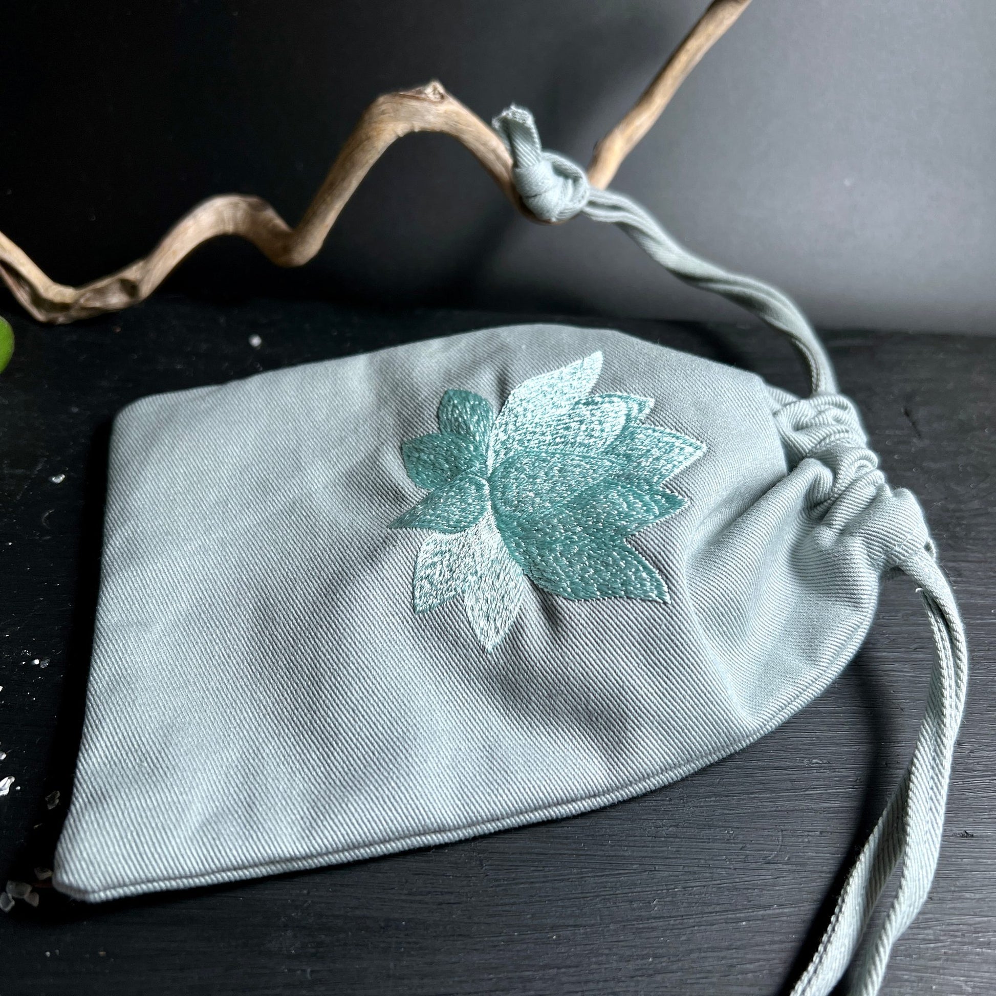 Detailansicht Stoffbeutel | türkise Lotusblüte Stickerei | grauer Stoff | geschlossener Kordelzug | Happy Minerals