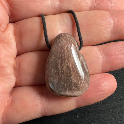 Mondstein Anhänger tropfenförmig, graubraun mit weissem Glanzstreifen, poliert, an schwarzer Kordel | Happy Minerals