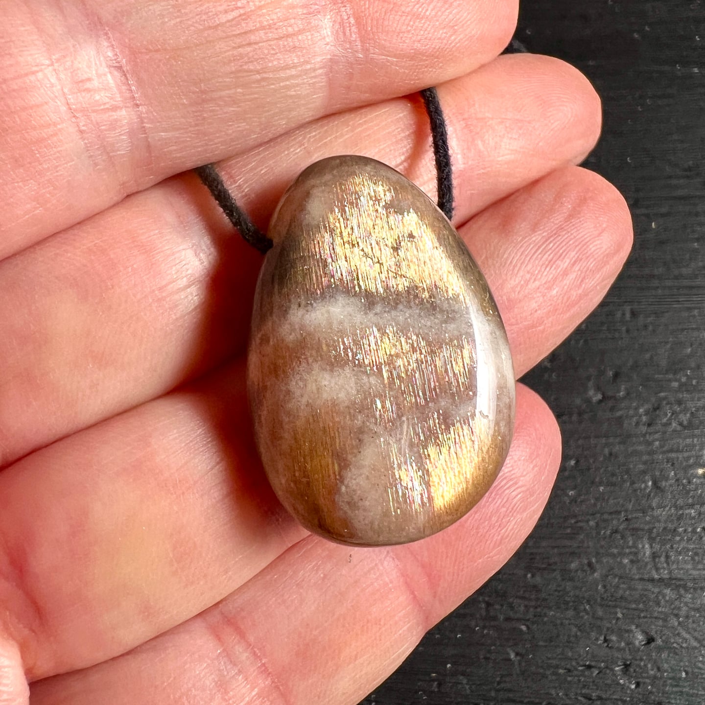 Mondstein Hand | warme Töne | magischer Glanz | schwarzes Band | Größenvergleich | Happy Minerals