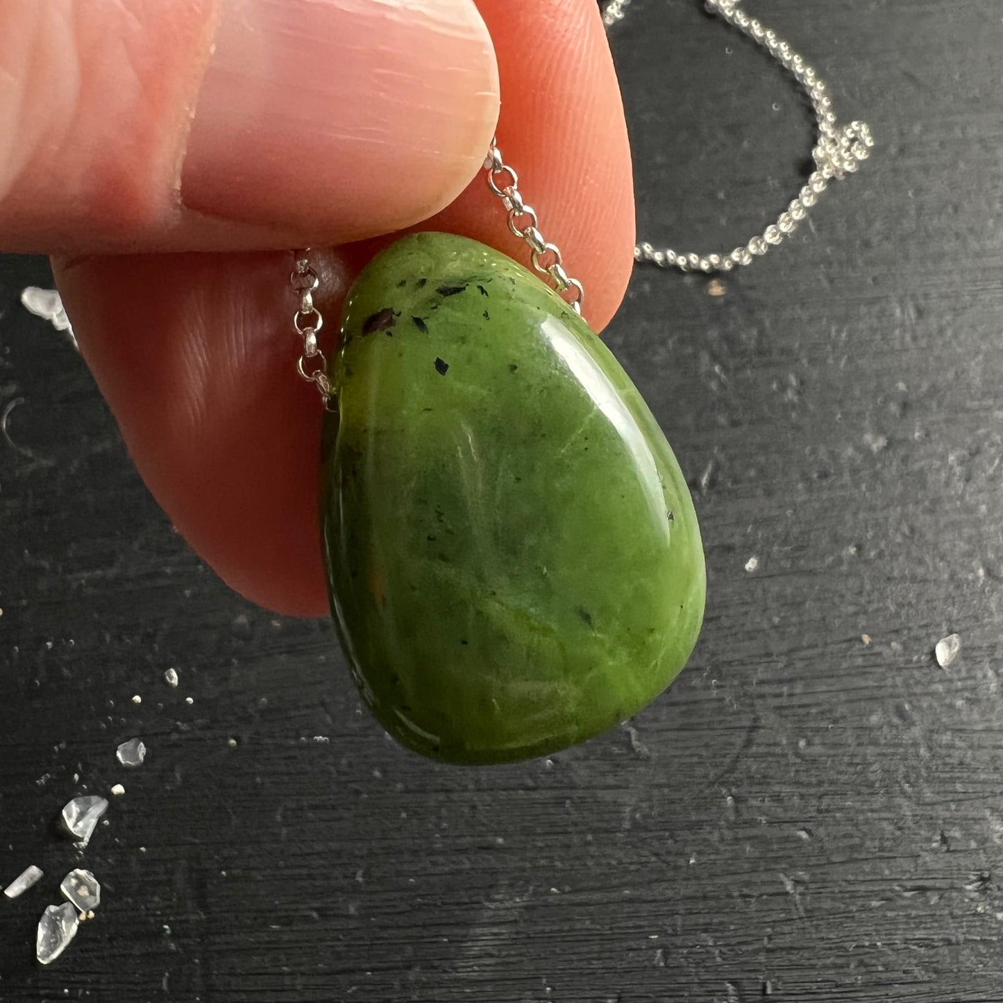 Nephrit Jade Kanada | zwischen Fingern gehalten | beide Seiten sichtbar | apfelgrün | Silberkette | Happy Minerals
