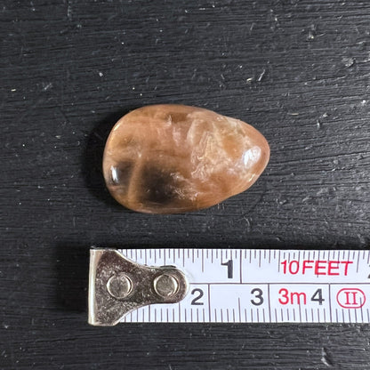 Orange Mondstein Anhaenger, unregelmaessig oval, honigbraun mit dunklen Wolkenzonen und Glanz | Happy Minerals