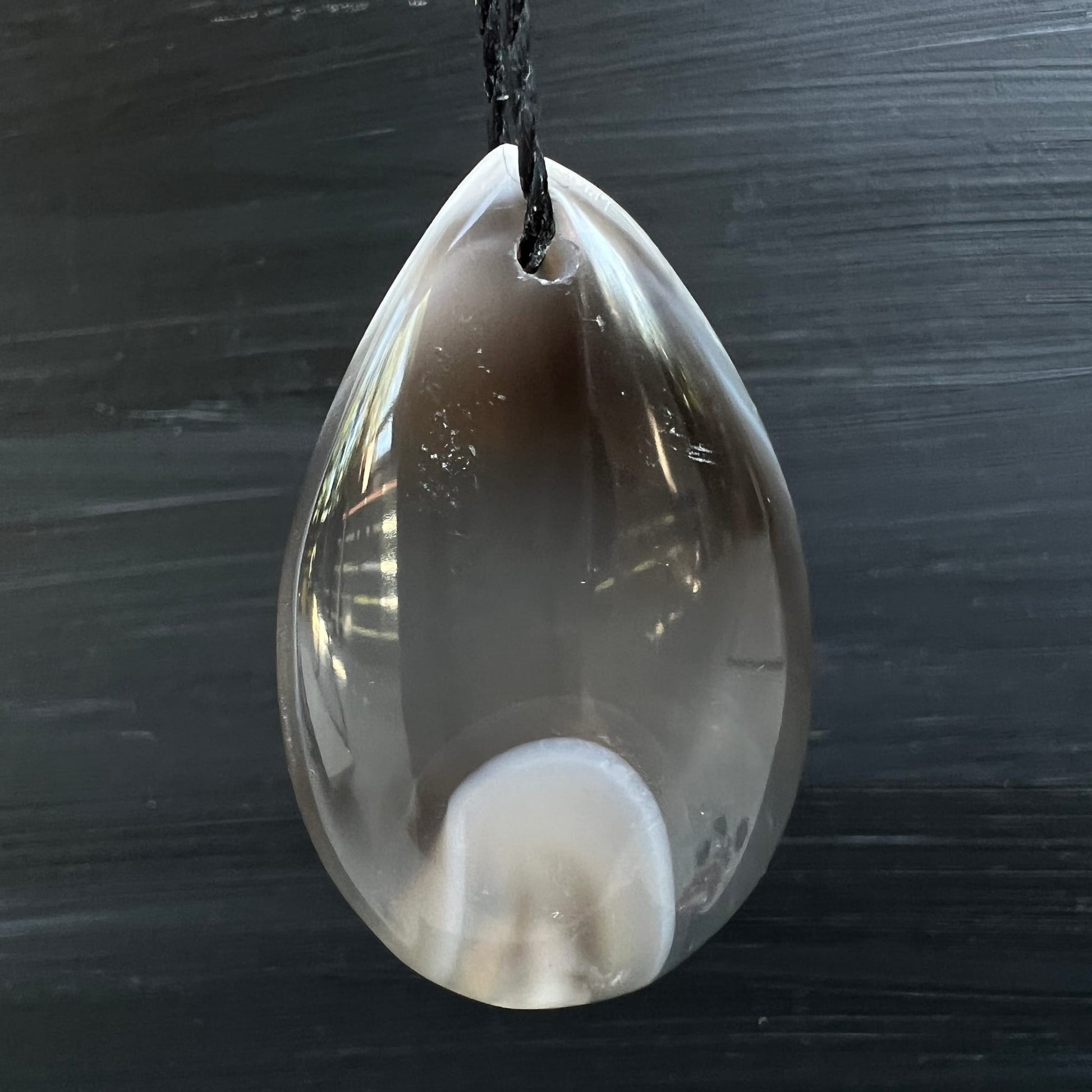Orca Achat Tropfen | hängend | schwarzer Hintergrund | weißes Oval | transluzent | Happy Minerals
