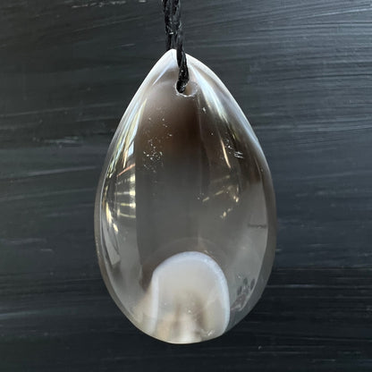 Orca Achat Tropfen | hängend | schwarzer Hintergrund | weißes Oval | transluzent | Happy Minerals