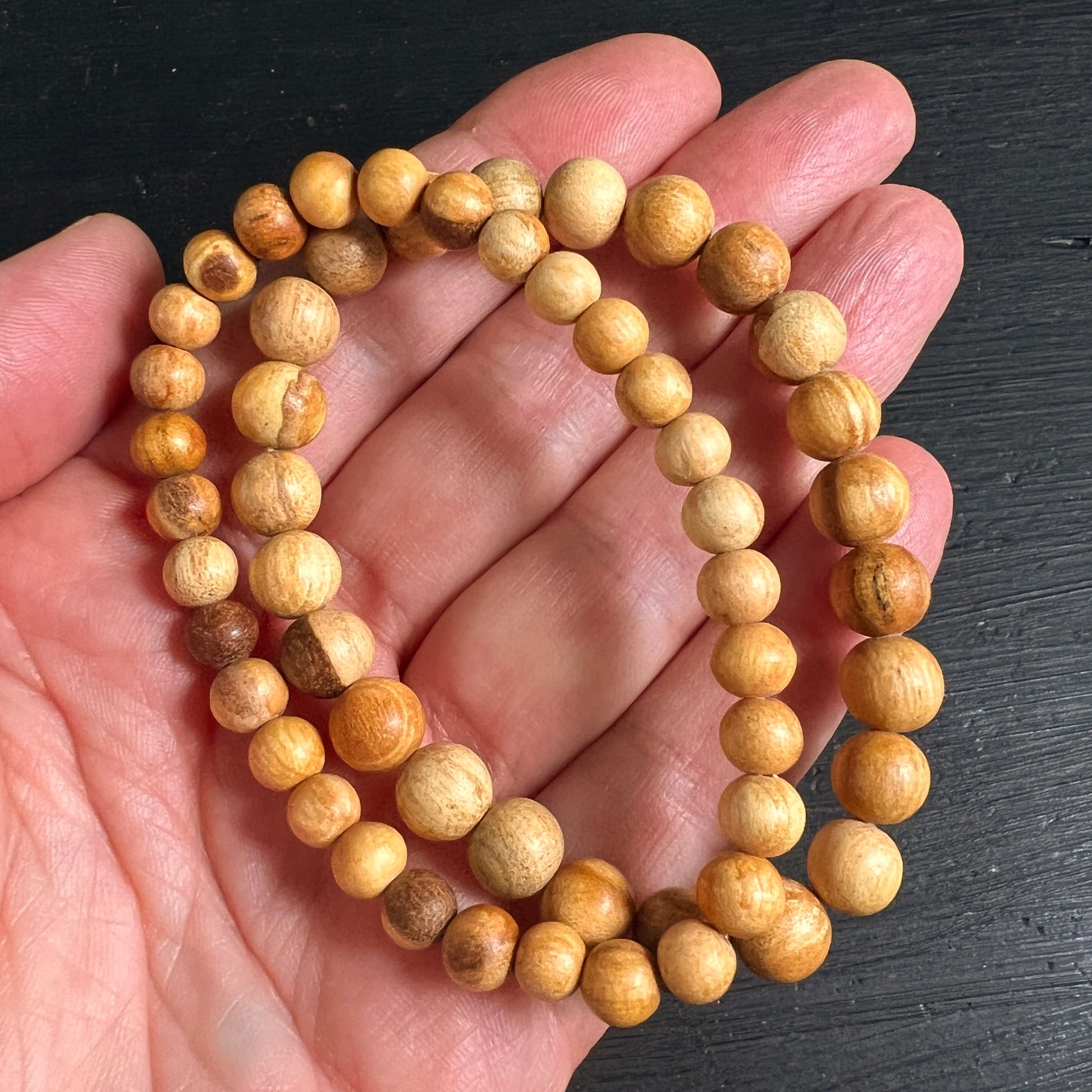 Palo Santo Armbänder in der Hand gehalten | warme Holzperlen | natürliche Maserung | Peru | Happy Minerals | Variante G