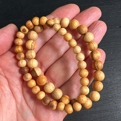 Palo Santo Armbänder in der Hand gehalten | warme Holzperlen | natürliche Maserung | Peru | Happy Minerals | Variante G