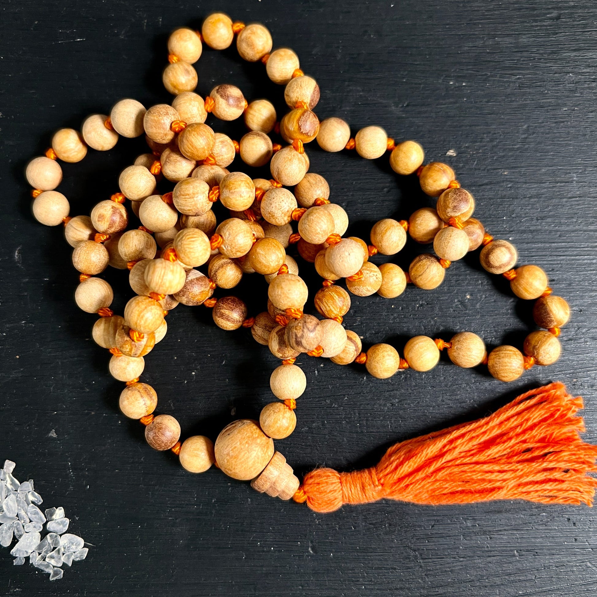 Palo Santo Mala | aufgerollt auf dunklem Untergrund | honigfarbene Holzperlen | Guru Perle | Happy Minerals