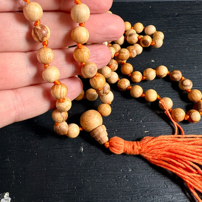Palo Santo Mala | in der Hand | einzelne Perlen mit Maserung | orangefarbene Seidenknoten | Happy Minerals