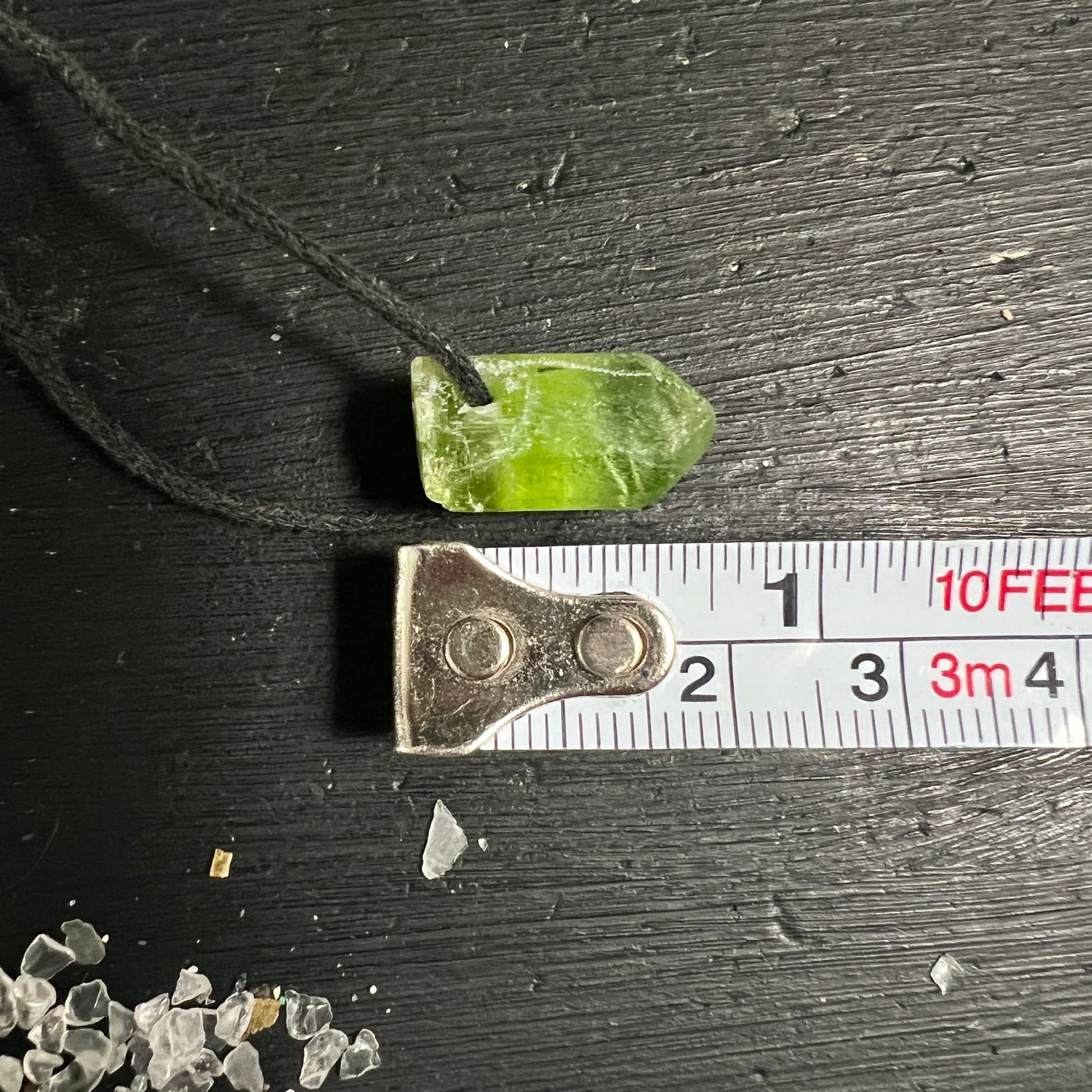 Peridot Rohstein grasgrün mit weißlichen Schlieren, spitz zulaufende Stabform, Bohrung für schwarze Kordel, ca. 2cm | Happy Minerals
