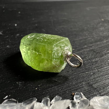 Peridot Rohstein grasgrün transparent, unregelmäßige Blockform, silberne Öse, Glasglanz, Einschlüsse sichtbar | Happy Minerals