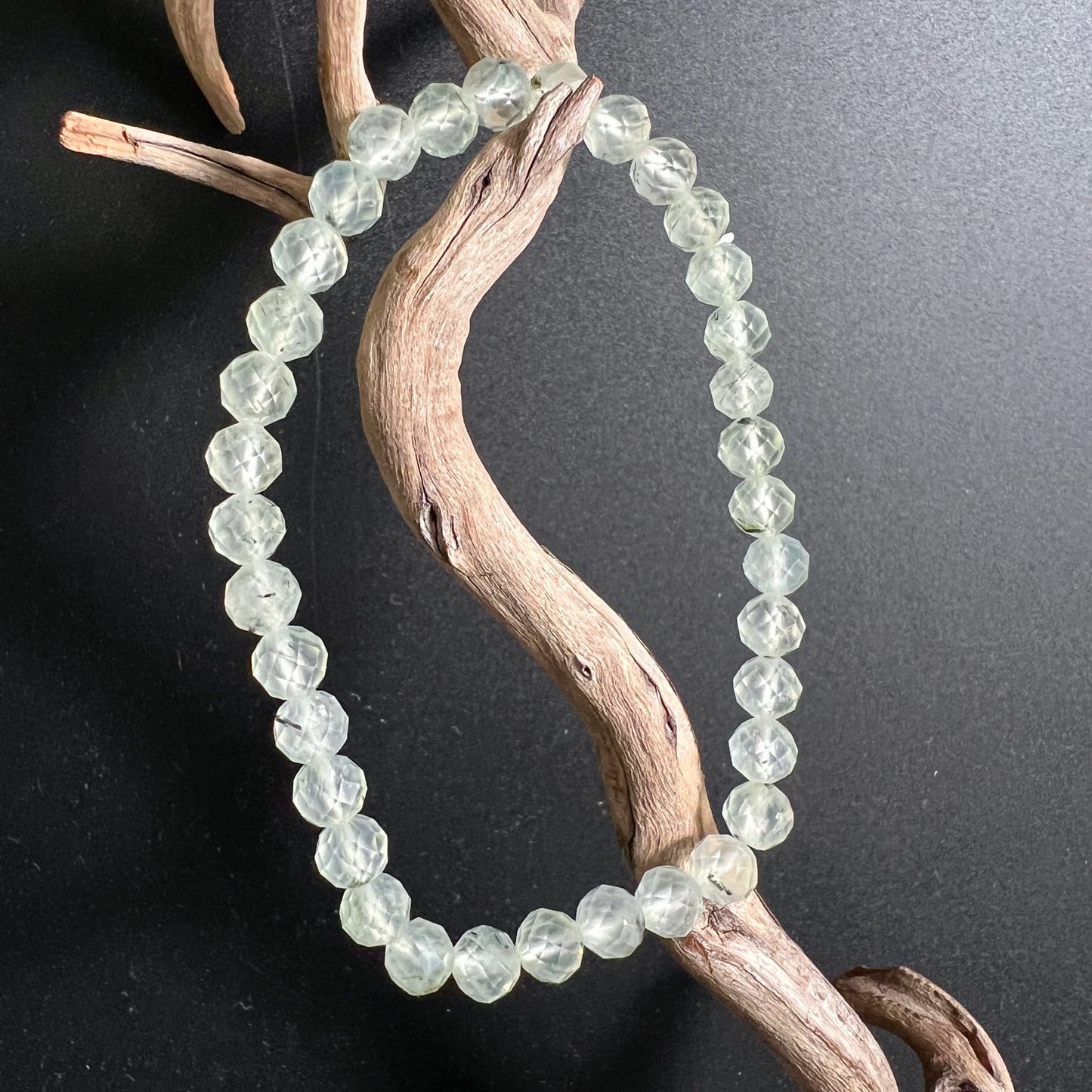 Prehnit Armband facettiert | drapiert auf Treibholz | zartes Eisgrün | schwarzer Hintergrund | Happy Minerals