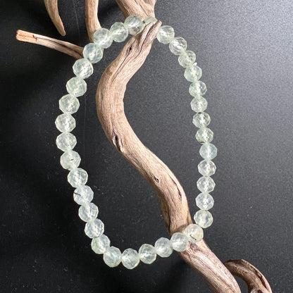 Prehnit Armband facettiert | drapiert auf Treibholz | zartes Eisgrün | schwarzer Hintergrund | Happy Minerals