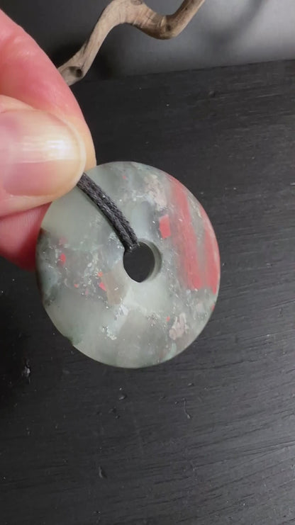 Heliotrop Donut Anhänger mit roten Jaspisadern und schwarzem Band.