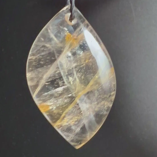 Golden Healer Quarz Anhänger mit goldenen Limonit-Einschlüssen auf dunklem Holz | Happy Minerals