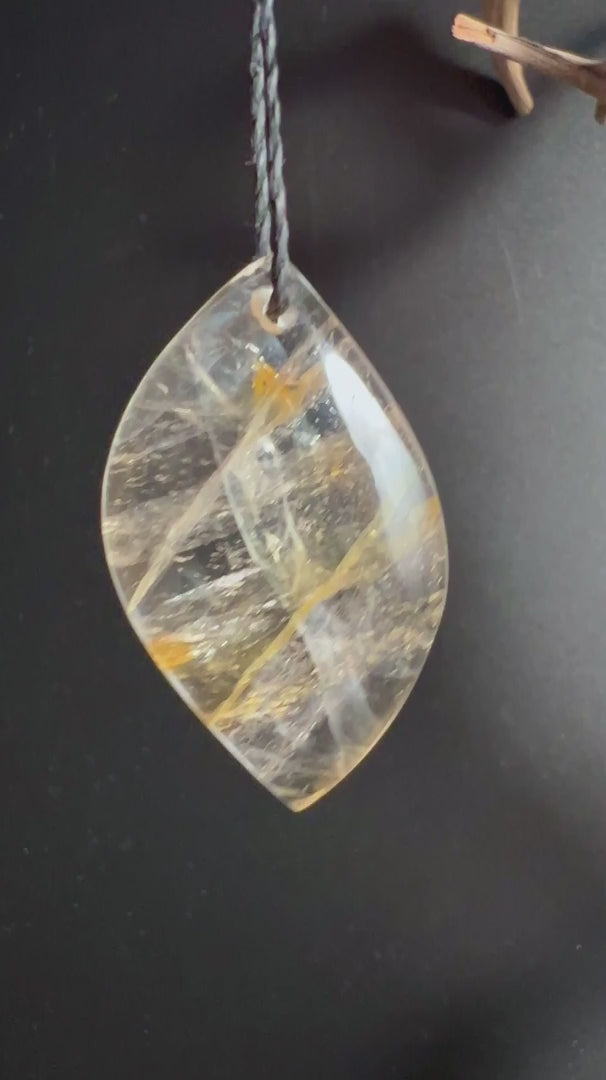 Golden Healer Quarz Anhänger mit goldenen Limonit-Einschlüssen auf dunklem Holz | Happy Minerals