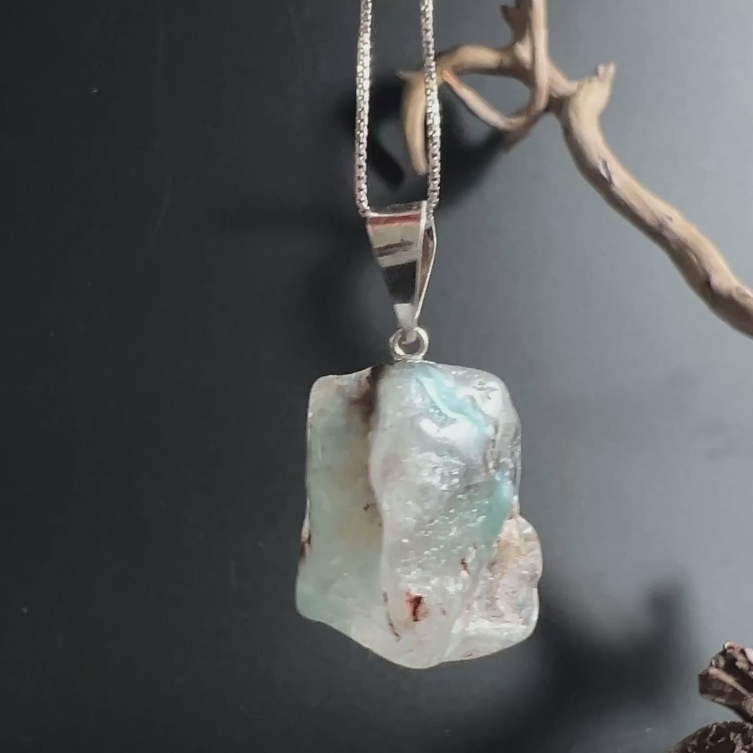 Video von Gilalit Kristall Anhänger mit zarten blauen Einschlüssen, schimmernd im Licht | Happy Minerals
