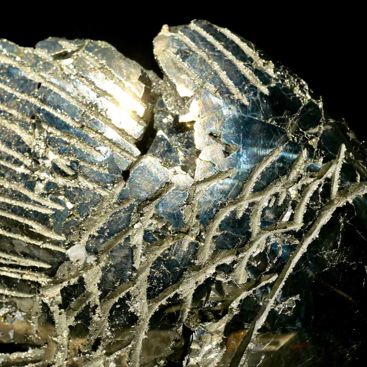 Pyrit Nahaufnahme mit metallisch-goldenem Glanz, gravierten Linienmustern und blaustichigen Facetten | Happy Minerals