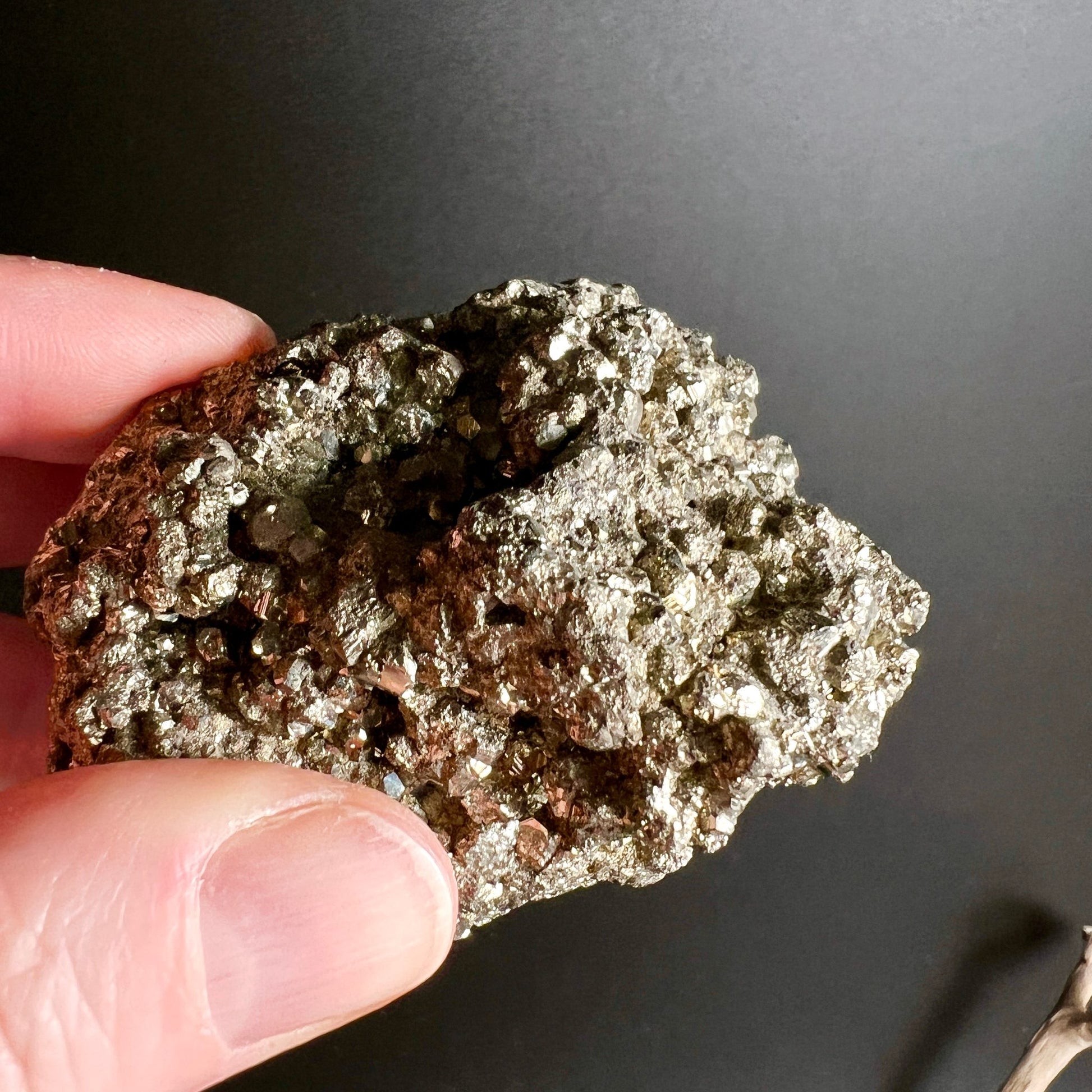 Pyrit Peru Kristallstufe | Hand zeigt Unterseite | rotbraune Matrix | metallische Kristallflächen | Happy Minerals