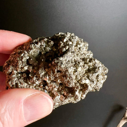 Pyrit Peru Kristallstufe | Hand zeigt Unterseite | rotbraune Matrix | metallische Kristallflächen | Happy Minerals