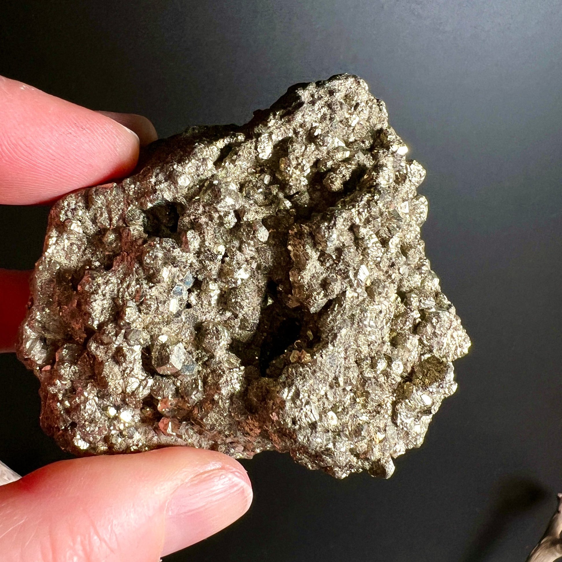 Pyrit Rohstein Peru Handhaltung | Größenvergleich Finger | rötlich braunes Muttergestein | Happy Minerals
