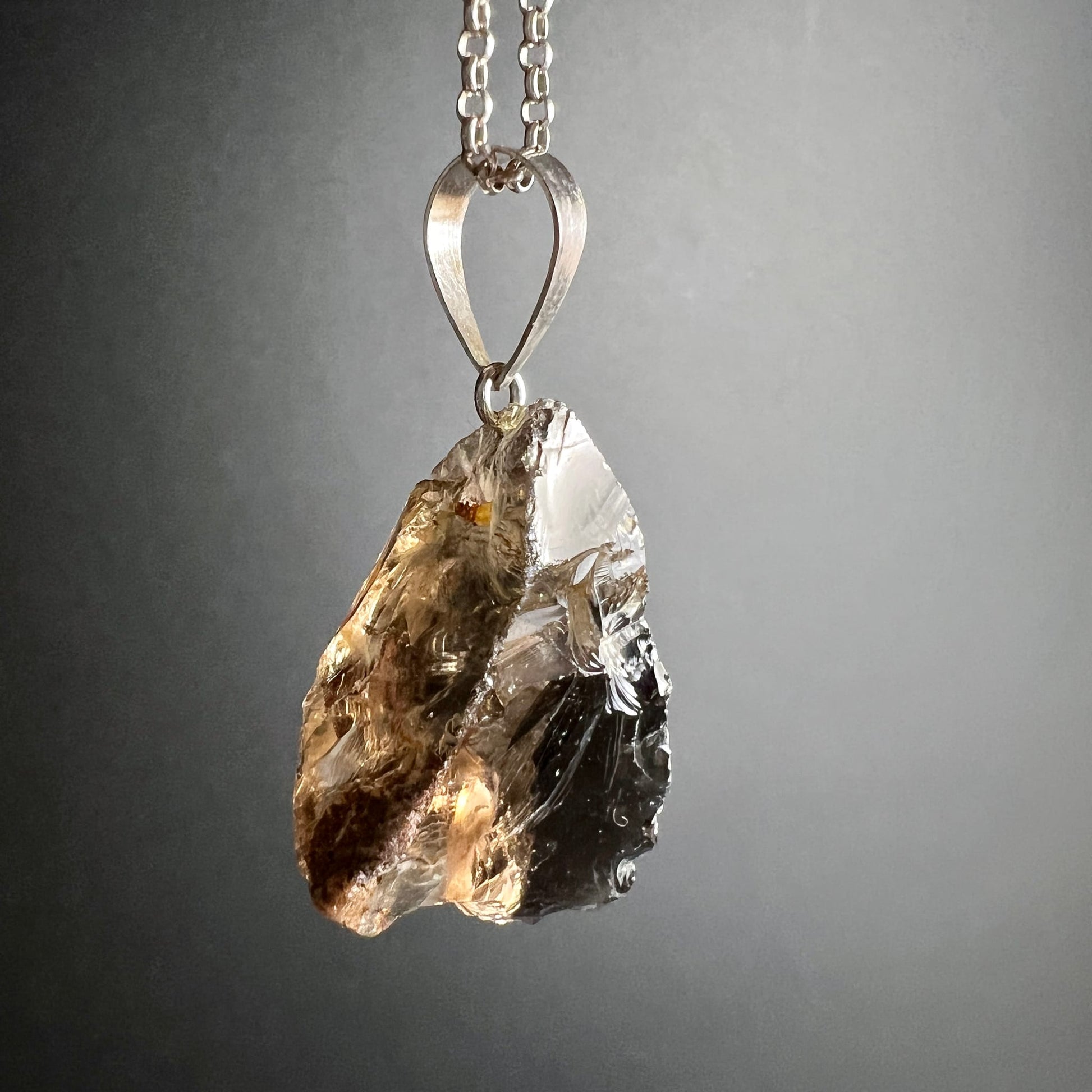 Rauchquarz Rohstein | hängend | warmes Bernsteinlicht | Silberkette | seitliche Ansicht links | Happy Minerals