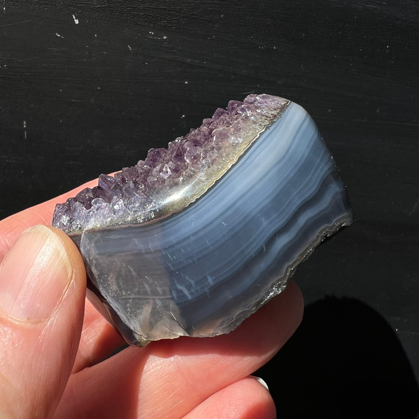 Regenbogen Amethyst Achat Uruguay | Hand hält Seitenansicht | violette Spitzen | polierte Achatbänder blau-grau | Happy Minerals