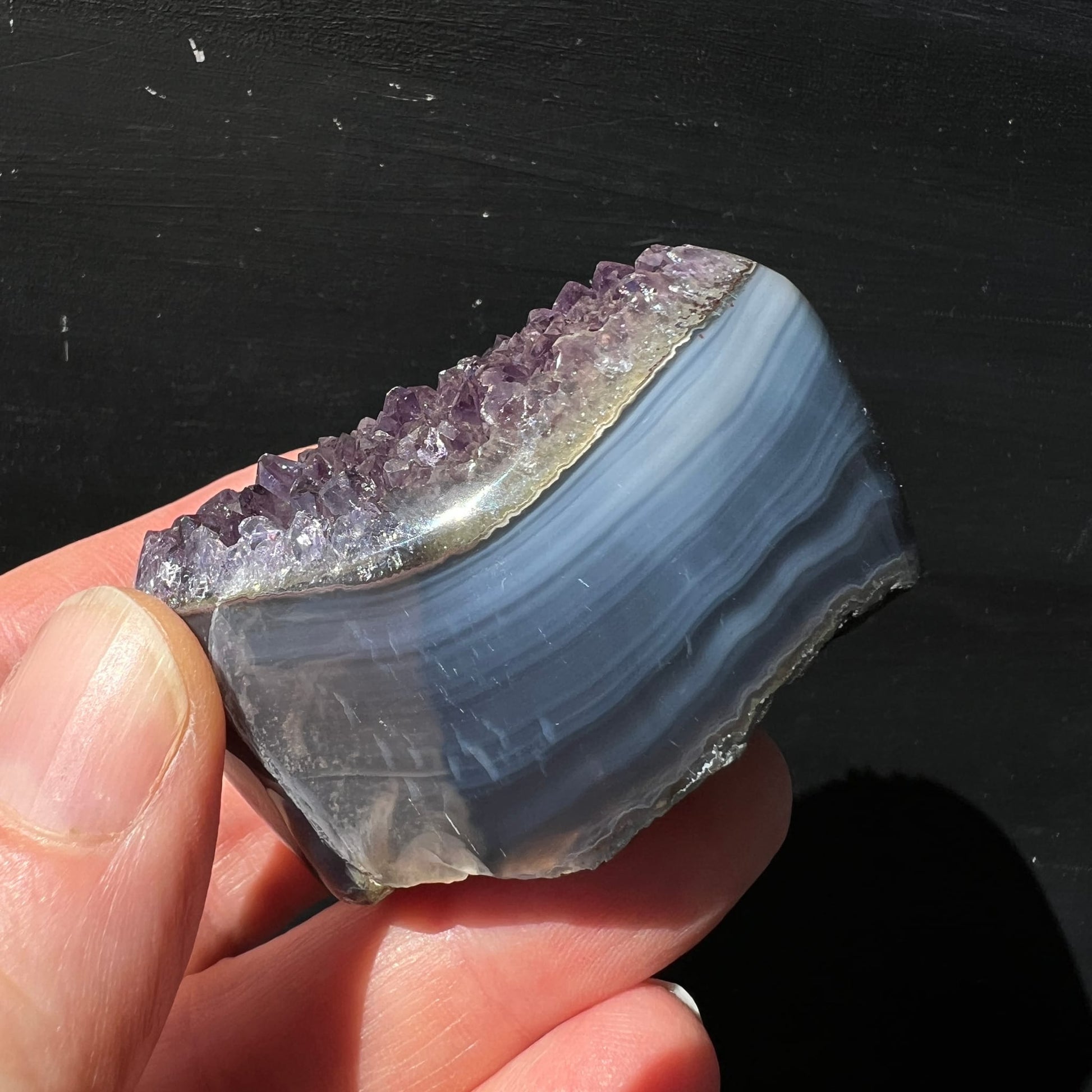 Regenbogen Amethyst Achat Uruguay | Hand hält Seitenansicht | violette Spitzen | polierte Achatbänder blau-grau | Happy Minerals