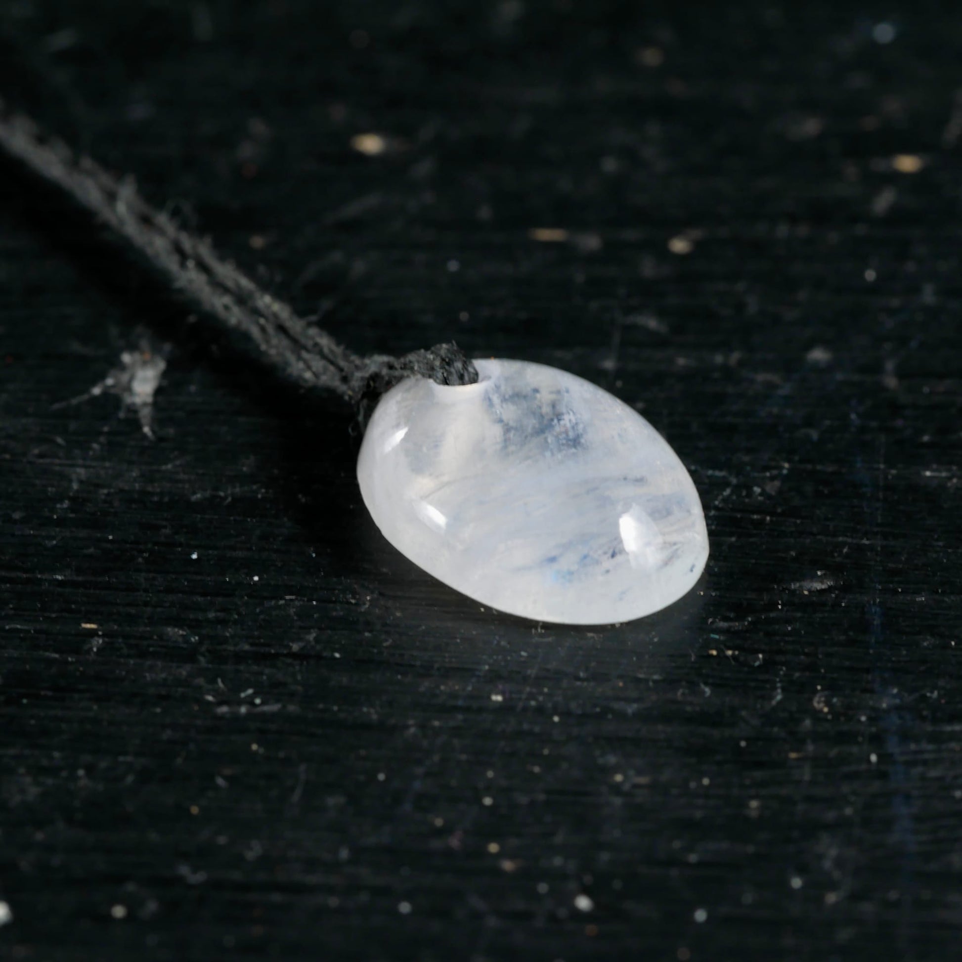 Mondstein Anhaenger oval poliert, milchig-weiss mit blauem Schimmer und Schlieren, an dunkler Kordel | Happy Minerals