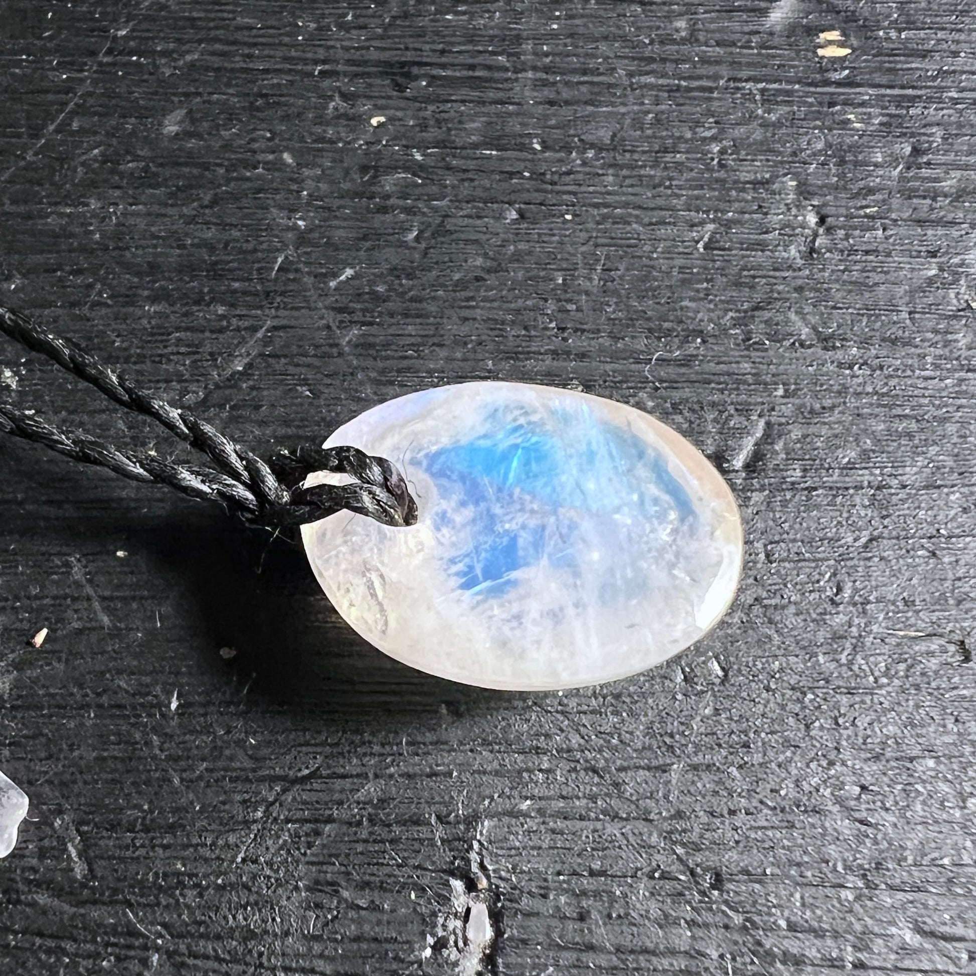Ovaler Mondstein Anhaenger, milchig-weiss mit blauem Schimmer und feinen Glanzstreifen, an schwarzer Kordel | Happy Minerals