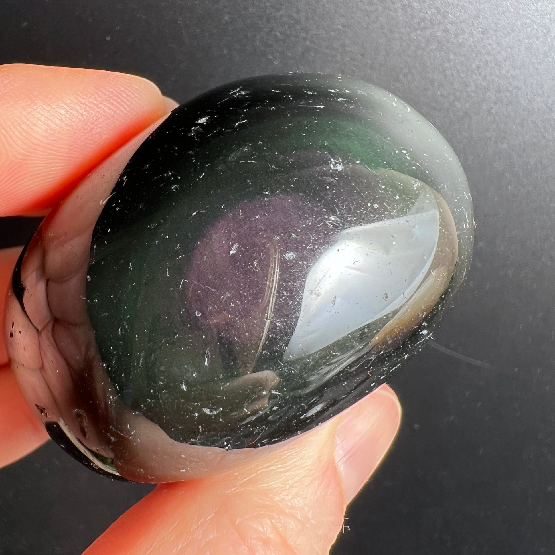 Regenbogenobsidian Trommelstein, tiefschwarz-dunkelgrün mit violettem Schimmer und silbrig-weißem Lichtreflex, oval poliert | Happy Minerals