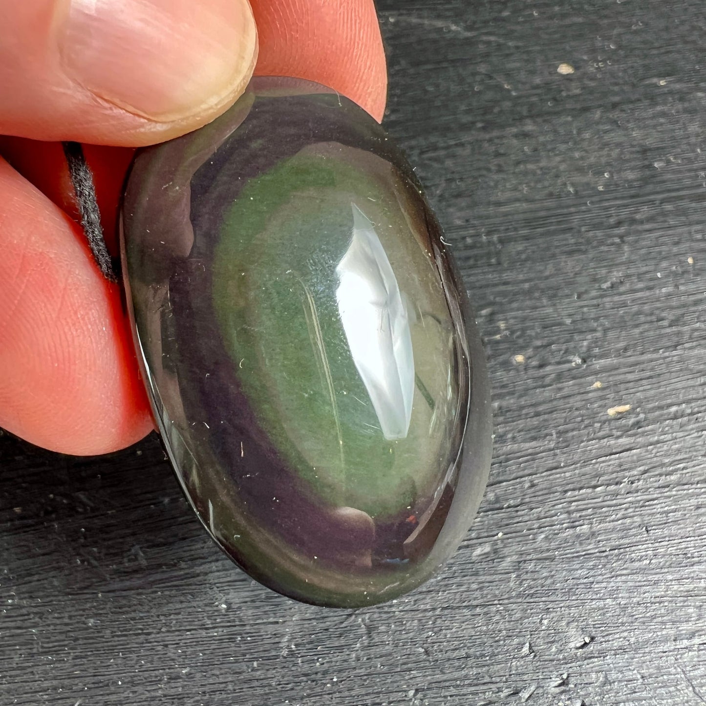Regenbogenobsidian Nahaufnahme | lebendiges Grün mit Violett-Rand | zwischen Fingern | Happy Minerals