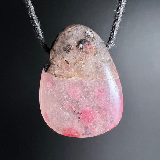 Rhodonit Anhänger in Tropfenform, oben grau-braun matt, unten rosa-pink glänzend mit dunklen Flecken | Happy Minerals
