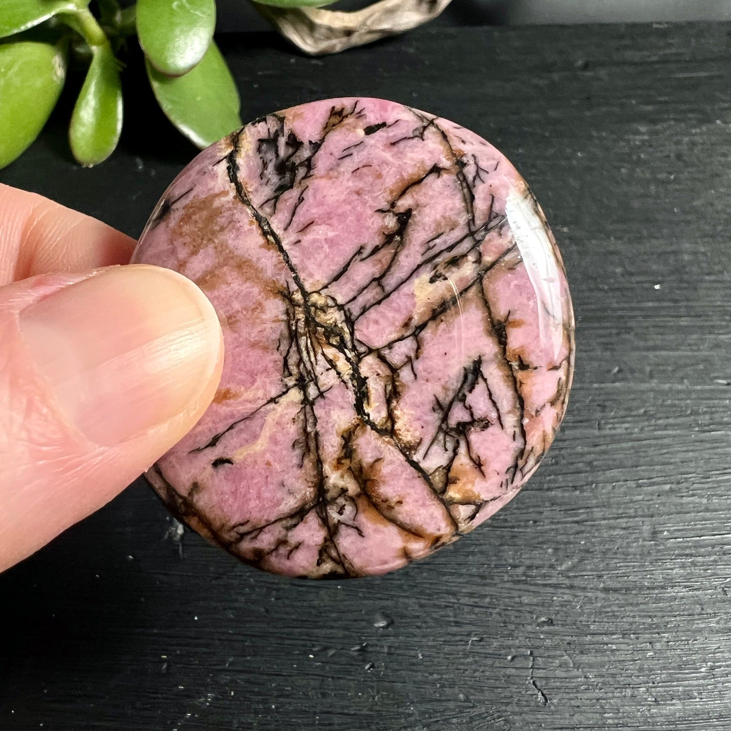 Rhodonit Handschmeichler | Hand zeigt Größe | rosa Grundfarbe | schwarze Maserung | Australien | Happy Minerals