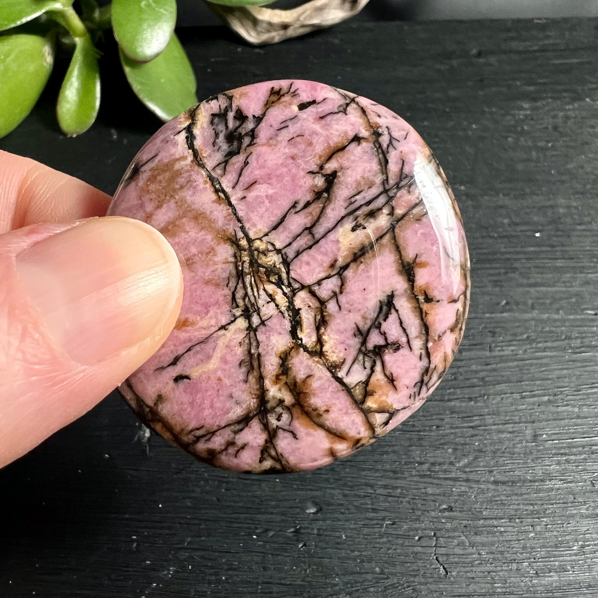 Rhodonit Handschmeichler | Hand zeigt Größe | rosa Grundfarbe | schwarze Maserung | Australien | Happy Minerals