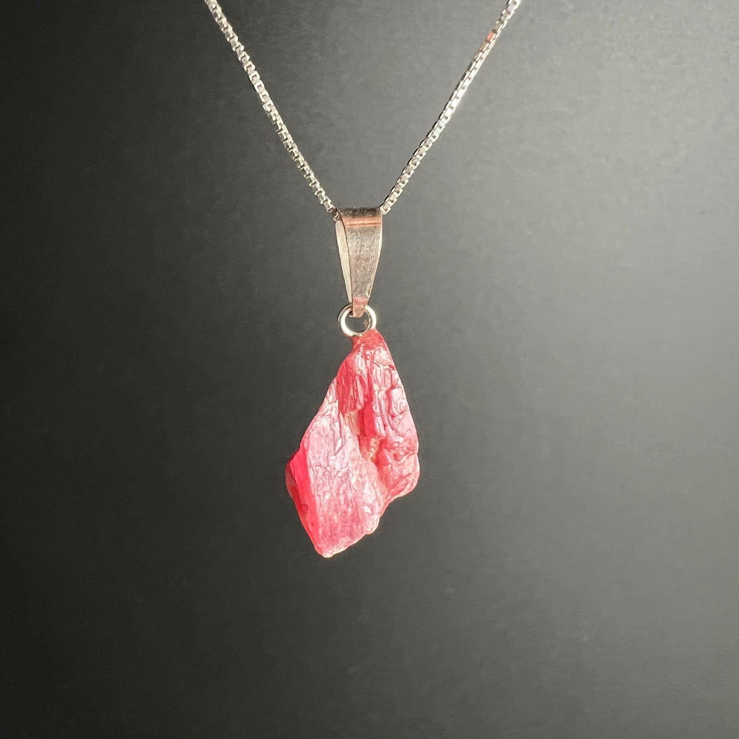 Rhodonit Kristall Anhänger | elegante Präsentation | Silberkette | grauer Hintergrund | Happy Minerals