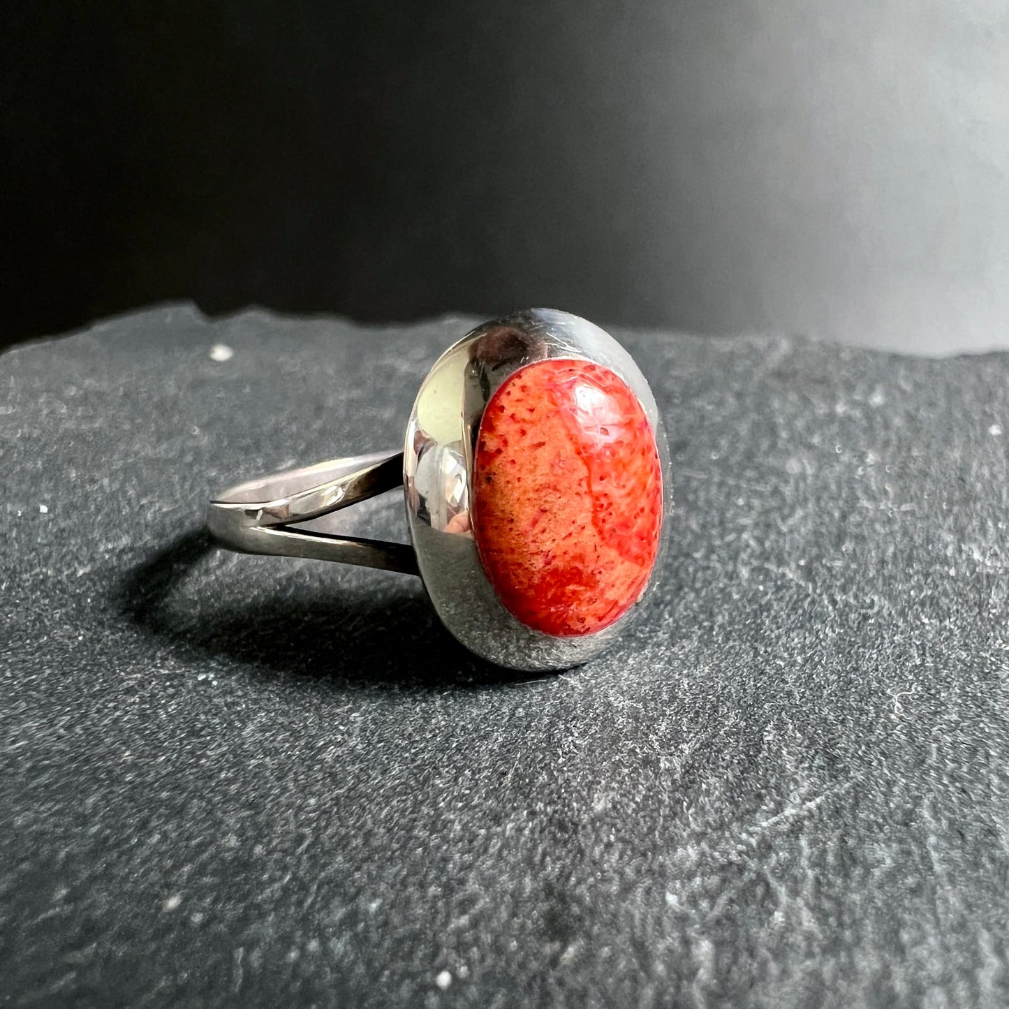 Nahaufnahme Korallenring | leuchtend rote Oberfläche | Silberfassung glänzend | auf Schiefer | Happy Minerals