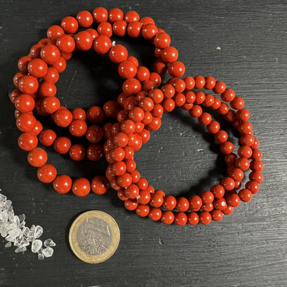 Roter Jaspis Namibia | leuchtend rote Kugelkette aufgerollt | Euro-Münze als Größenvergleich | Happy Minerals