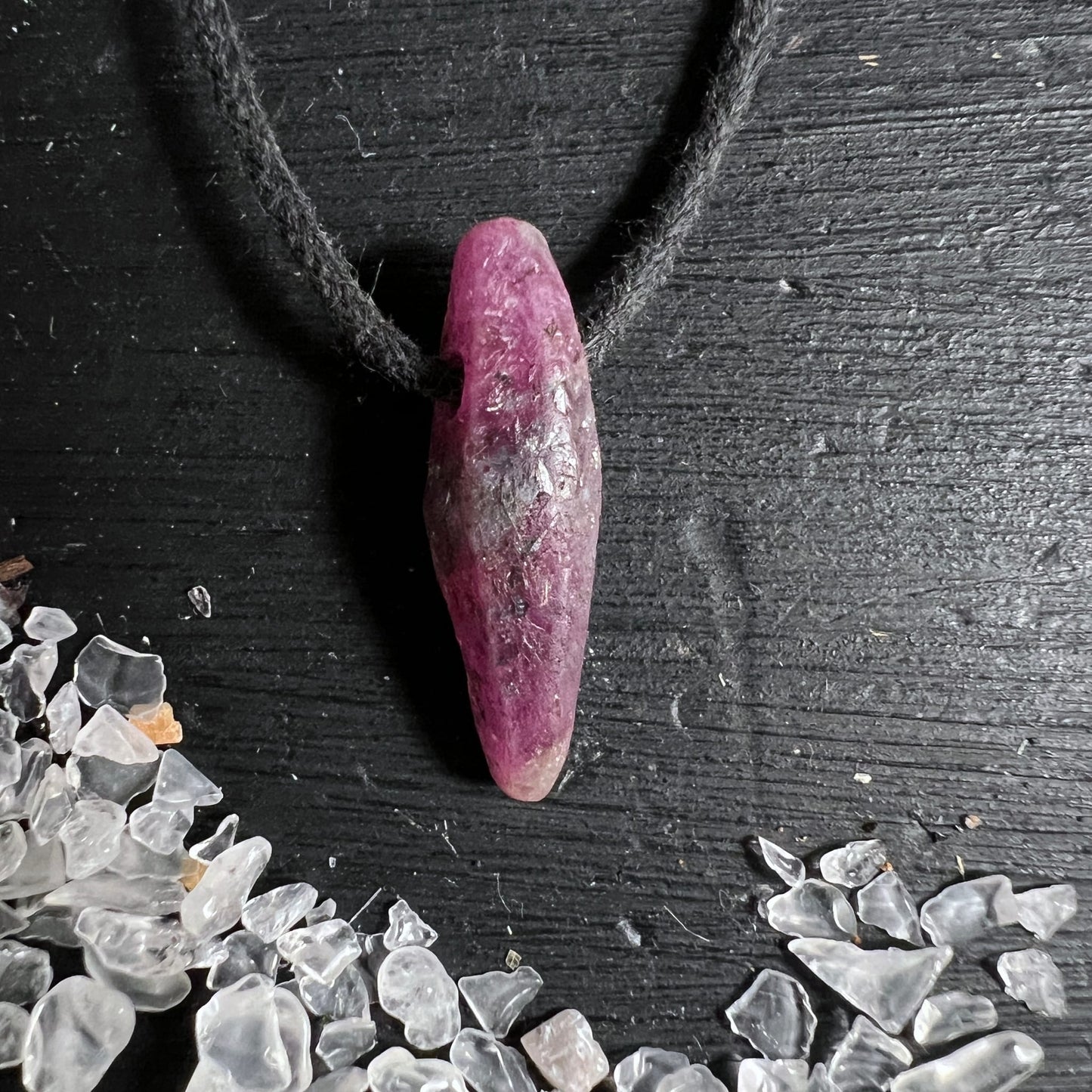 Rubin Rohstein Mali | zartes Rosa-Violett | schwarze Kordel | Bergkristalle im Hintergrund | Happy Minerals