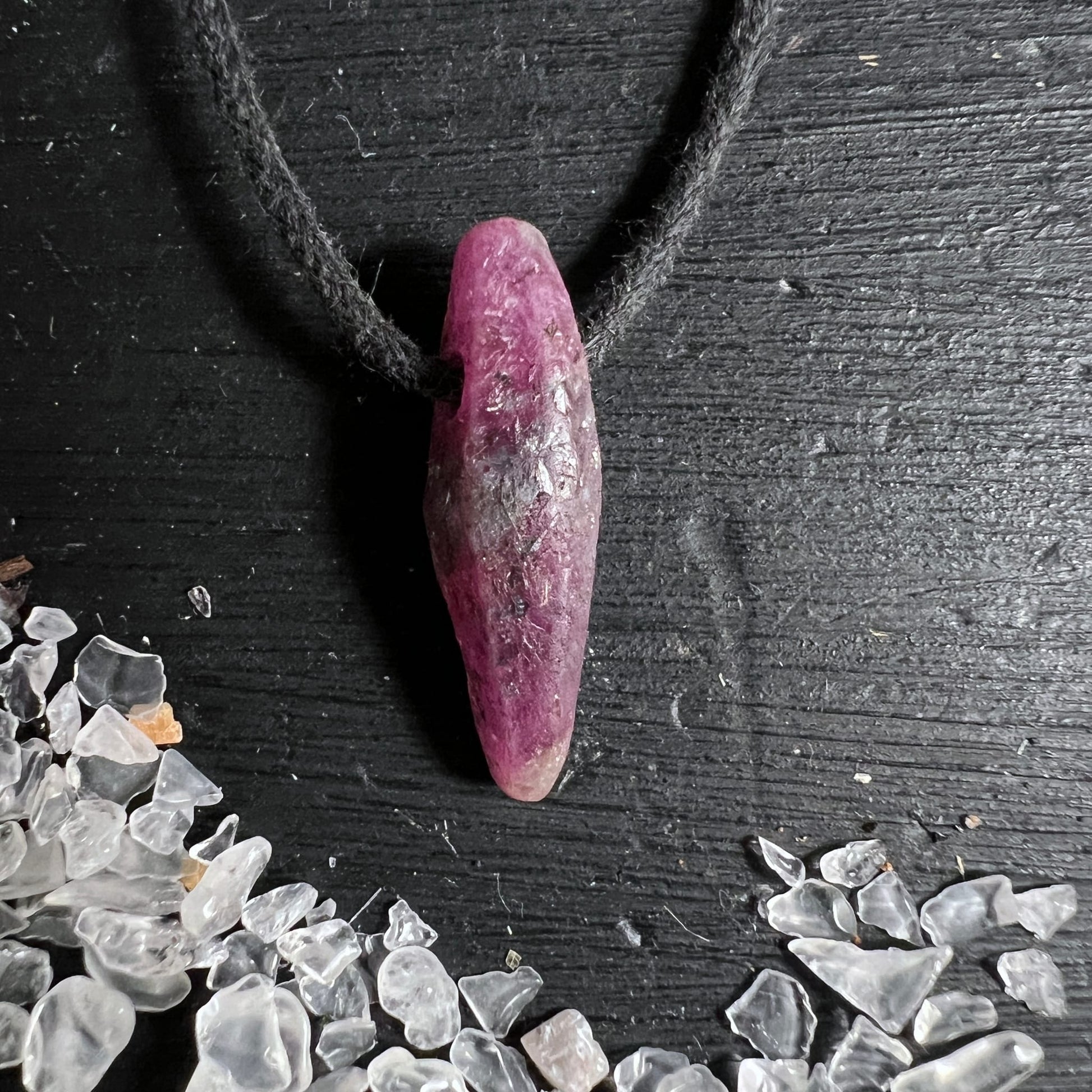 Rubin Rohstein Mali | zartes Rosa-Violett | schwarze Kordel | Bergkristalle im Hintergrund | Happy Minerals