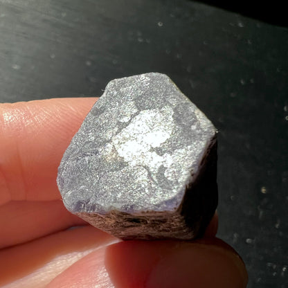 Roher Saphirkristall mit metallisch glänzender grauer Oberflaeche und violetten Kanten, Pentagonform | Happy Minerals