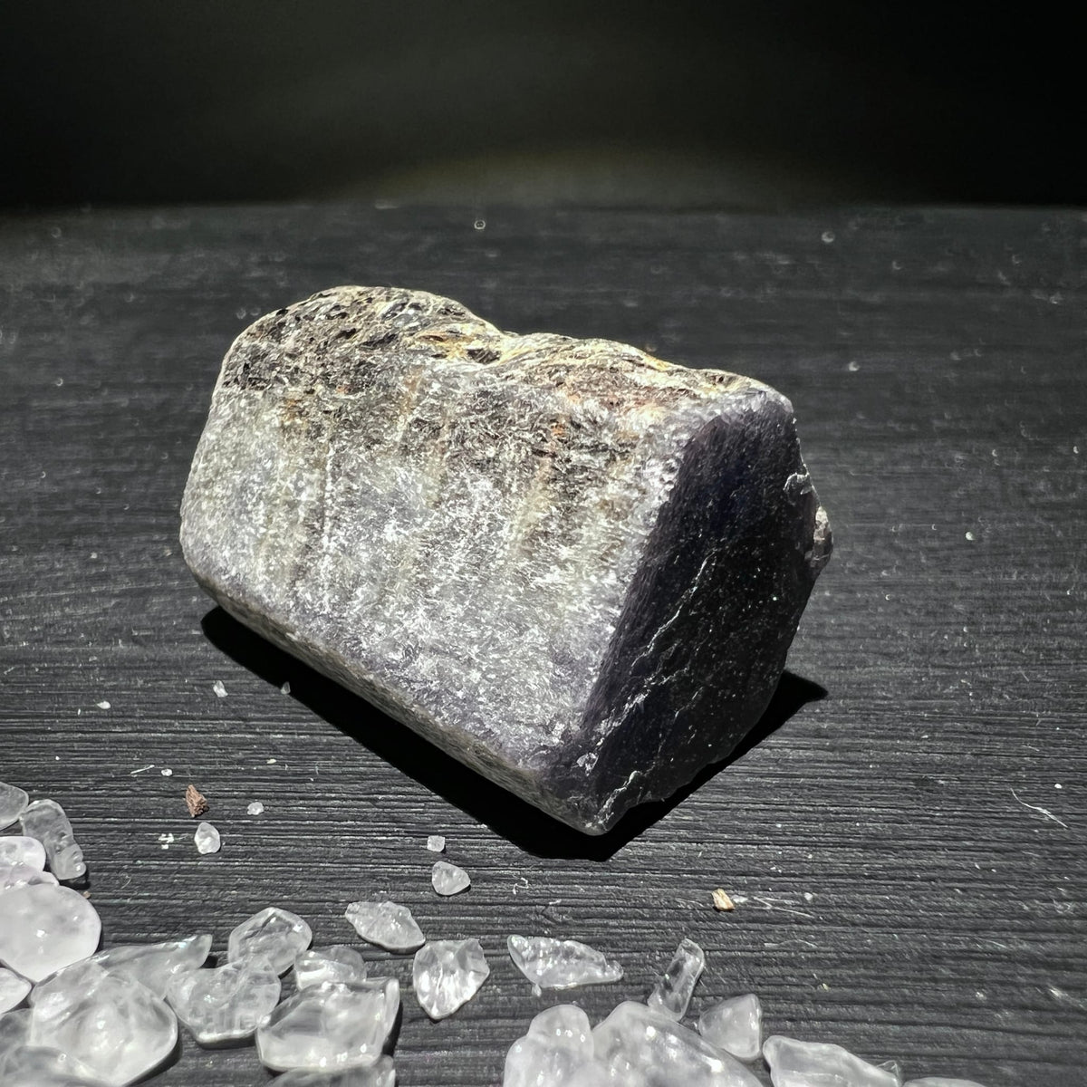 Roher Saphirstein mit grau-silbrig glimmernder Oberflaeche und dunkler kristalliner Bruchkante | Happy Minerals