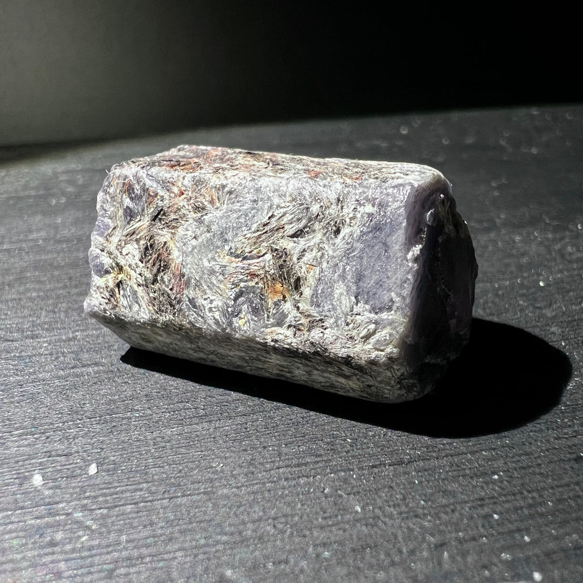 Roher Saphir Kristall in Blockform, graulila mit silbrig-faserigen Glimmereinschluessen und rostbraunen Adern | Happy Minerals