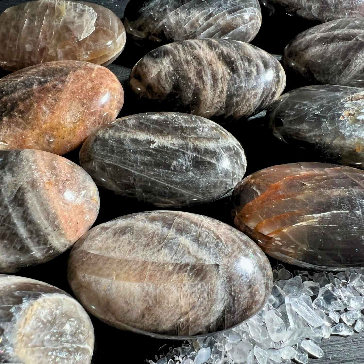Schwarze Mondstein Palm Stones mit Peach Einschlüssen auf dunklem Grund